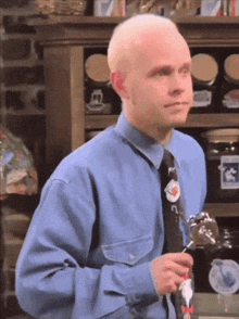 a man in a blue shirt and tie holds a spoon