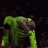 a wrestler in a green outfit is jumping over another wrestler in an impact ring