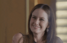 a woman wearing a black dress and earrings smiles
