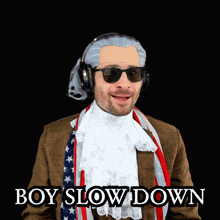 a man in a suit and scarf is wearing sunglasses and headphones and says " boy slow down "