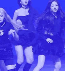 a group of young women are dancing on a stage with a blue background .