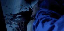 a man in a blue shirt is looking at a bloody screen