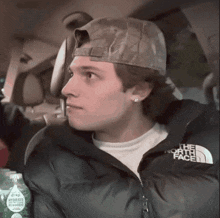 a man wearing a hat and a north face jacket is sitting in a car