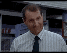 a man in a striped shirt and tie is smiling and looking at the camera .