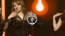 a woman in a black dress is standing in front of a microphone that says ' a & r ' on it