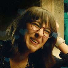 a close up of a woman wearing glasses with hearts around her