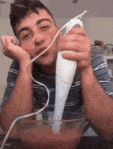 a young man is using a blender to mix something