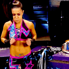 a woman in a wrestling outfit is standing next to a purple trunk with a championship belt on it .