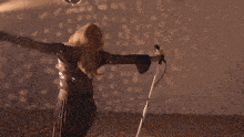 a woman singing into a microphone with her arms up
