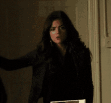 a woman in a black jacket stands in a doorway