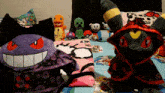 a purple stuffed animal with red eyes is sitting on a bed with other stuffed animals