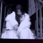 a black and white photo of a woman in a white fur coat holding a microphone