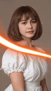 a woman in a white dress looks at the camera with a red light behind her