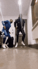 two men are jumping in the air in a hallway with tik tok written on the bottom