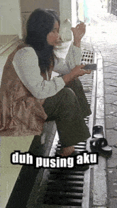 a woman sitting on a drain with the words duh pusing aku written on the bottom