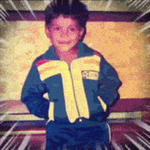 a young boy is wearing a blue and yellow jacket with a soccer ball on it .