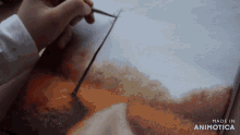 a person is painting on a canvas with the words made in animotica in the corner