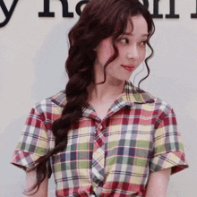 a woman wearing a plaid shirt stands in front of a sign that says ' y ' on it
