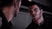 two men are looking at each other in a dark room
