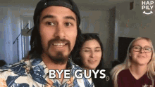 a man in a hawaiian shirt is standing in front of two women and says bye guys .