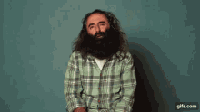 a man with a beard wearing a green plaid shirt is smiling in front of an abc life ad