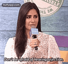 a woman is holding a microphone and talking into it .