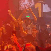a man making a heart shape with his hands in a crowd