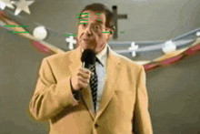 a man in a suit and tie speaking into a microphone with a cross in the background