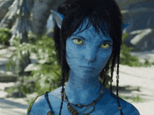 a woman with a blue face and green eyes is wearing a necklace