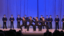 a group of men in navy uniforms are performing on stage