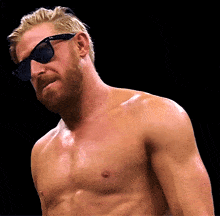 a shirtless man wearing ray-ban sunglasses looks at the camera