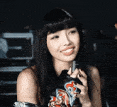 a woman with long black hair is smiling and holding a cell phone in her hand