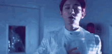a young man in a white shirt is standing in a dark room .