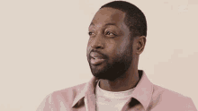 a man wearing a pink shirt has the letter e on his chest