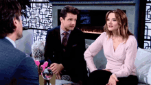 a man and a woman sit on a couch talking to each other
