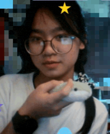 a girl wearing glasses holds a stuffed animal with a yellow star on her head