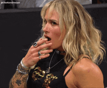 a woman with a tattoo on her arm is wearing a black shirt with gold letters