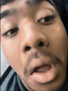 a close up of a man 's face with his mouth open and a black spot on his face