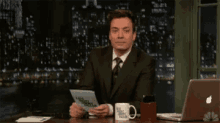 jimmy fallon is sitting at a desk with a laptop