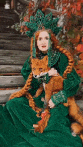 a woman in a green dress holds a fox in her arms