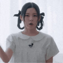 a woman in a white dress with pigtails and a microphone on her neck .