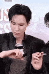 a man in a black jacket is holding a lighter in his hand .