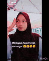 a woman wearing a hijab has a tiktok sticker on her face