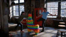 two men are fighting over a colorful piñata in a room with a sign that says danger