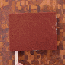 a person is cutting a piece of cake with a knife on a cutting board