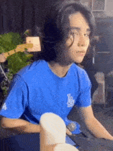 a young man with long hair is wearing a blue t-shirt and playing a keyboard .