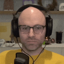 a bald man wearing glasses and headphones looks angry