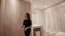 a woman in a black dress is standing in a bedroom next to a dressing table .