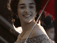 a woman wearing a necklace and earrings smiles with a red umbrella in the background