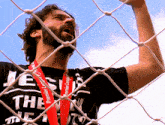 a man wearing a black shirt with the word jesus on it is behind a soccer net